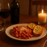 Served plate of baked ziti with garlic bread and wine
